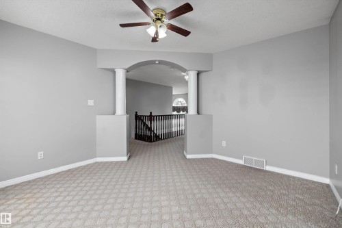 Carpeted interior space featuring an architectural archway with decorative columns - 4831 154 Avenue, Edmonton, AB 