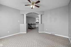 Carpeted interior space featuring an architectural archway with decorative columns - 