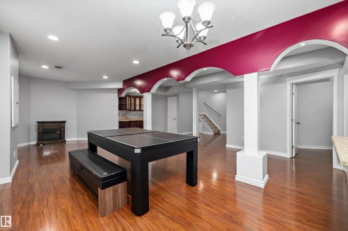 Open-concept lower level with wood-finish flooring, recessed lighting, and a prominent chandelier - 4831 154 Avenue, Edmonton, AB 