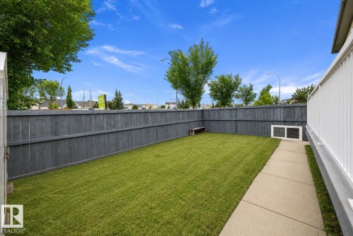 Private backyard featuring a well-maintained lawn, a paved walkway, and a dark stained wooden fence - 4831 154 Avenue, Edmonton, AB 