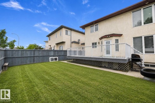 Expansive backyard featuring a manicured lawn, full-height privacy fence, and a spacious elevated deck with white railings - 4831 154 Avenue, Edmonton, AB 