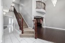Grand foyer featuring a curved upper balcony, a two-story ceiling, and a prominent staircase with wood railings and carpeted treads - 4831 154 Avenue, Edmonton, AB 