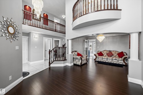 Two-story entry featuring dark wood-finish flooring, a grand staircase with wood balusters, and an upper-level overlook - 4831 154 Avenue, Edmonton, AB 