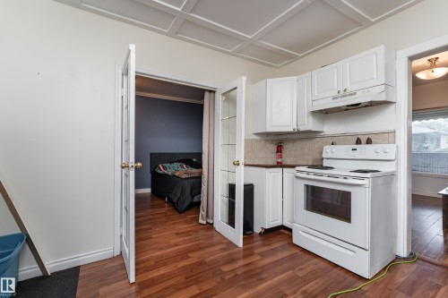 Compact kitchen featuring white cabinetry, a white electric range, and a neutral tile backsplash - 11406 89 Street, Edmonton, AB 
