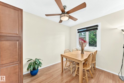 Dining area featuring wood-finish flooring, a window with black blinds, and a ceiling fan with integrated lighting - 102 Royal Terrace, Edmonton, AB 