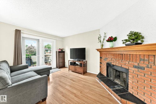 Living area featuring a brick fireplace with a wood mantle and black stone hearth - 102 Royal Terrace, Edmonton, AB 