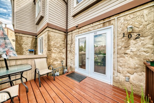 Private patio featuring durable wood-finish decking and direct access through double glass-paneled doors - 102 Royal Terrace, Edmonton, AB 