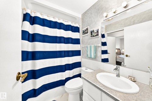 Bathroom featuring a single vanity with an oval sink, a wall-mounted mirror, and a three-bulb vanity light fixture - 102 Royal Terrace, Edmonton, AB 