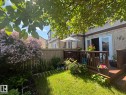Private backyard space featuring a wooden privacy fence, a verdant lawn area, and mature flowering shrubs - 102 Royal Terrace, Edmonton, AB 