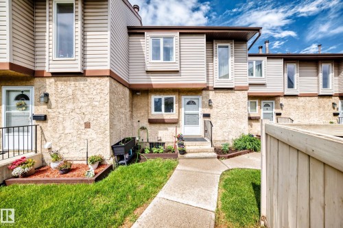 Townhouse exterior featuring a concrete pathway, a stucco and siding facade, and a raised flower bed - 102 Royal Terrace, Edmonton, AB 