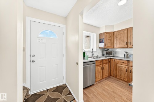 Entryway featuring a paneled door with an arched transom window, chrome hardware, and light neutral wall tones - 102 Royal Terrace, Edmonton, AB 