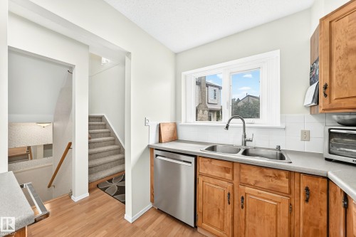 Kitchen featuring wood-finish flooring, light wood cabinetry, and a double basin stainless steel sink with a gooseneck faucet - 102 Royal Terrace, Edmonton, AB 