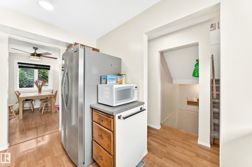 Wood-finish flooring throughout, with a stainless steel refrigerator, and wood-finish cabinetry - 102 Royal Terrace, Edmonton, AB 