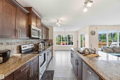Kitchen featuring wood-finish cabinetry, stainless steel appliances, granite countertops, and a tile backsplash - 5120 19 Avenue, Edmonton, AB 