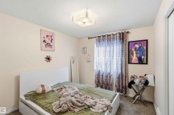 Bedroom featuring a white platform bed frame, a single window with blinds and patterned drapes, textured carpeting, and a flush mount ceiling light fixture - 