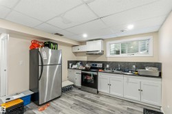 Kitchenette featuring white cabinetry, a stainless steel refrigerator, and a built-in range - 
