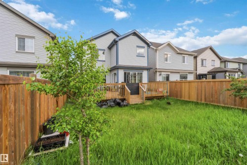Private backyard featuring a full wood fence, a large wood deck with steps, and a mature tree - 5120 19 Avenue, Edmonton, AB 