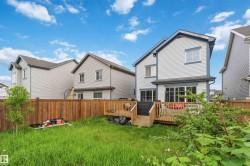 Rear exterior featuring a spacious wood deck, sliding glass doors, white horizontal siding, and a private wood fence - 