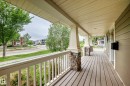 Inviting front porch featuring wood-finish decking, stone-clad pillars, white balusters. - 2523 Pegasus Boulevard, Edmonton, AB 