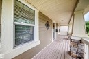 Covered front porch featuring wood-finish flooring, stone-clad pillar bases, and light-toned siding - 2523 Pegasus Boulevard, Edmonton, AB 