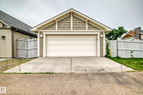 Detached two-car garage with a panel-style garage door, featuring horizontal siding, decorative shingle accents, and an A-frame roof - 2523 Pegasus Boulevard, Edmonton, AB 