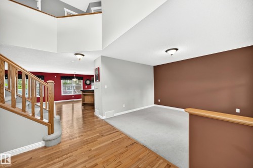 Two-story entryway featuring a wood-finish staircase with carpeted treads - 2523 Pegasus Boulevard, Edmonton, AB 