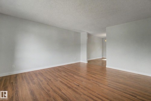 Spacious interior featuring wood-finish flooring, white baseboards, and light gray walls - 1511 75 Street, Edmonton, AB 