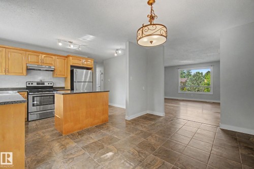 Kitchen featuring wood cabinetry, stainless steel appliances, and dark countertops - 1511 75 Street, Edmonton, AB 