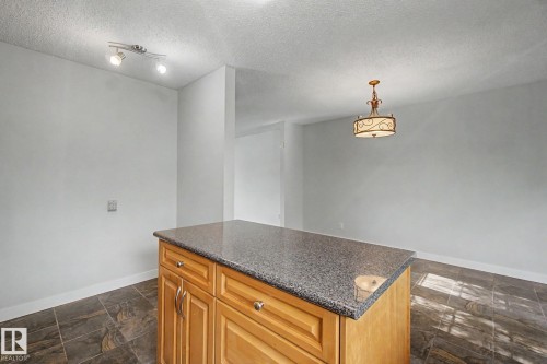 Central kitchen island with wood-finish cabinetry and a speckled countertop - 1511 75 Street, Edmonton, AB 