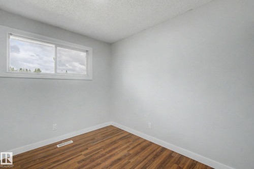 Windowed room featuring wood-finish flooring, light gray walls, white baseboards, and a white window frame - 1511 75 Street, Edmonton, AB 