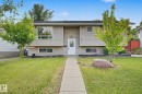 Split-level residence featuring light-toned horizontal siding, a central white entry door, and a concrete pathway - 1511 75 Street, Edmonton, AB 