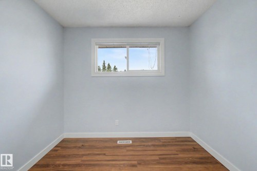 Room featuring wood-finish flooring, light blue wall paint, white baseboards, and a window with white trim - 1511 75 Street, Edmonton, AB 