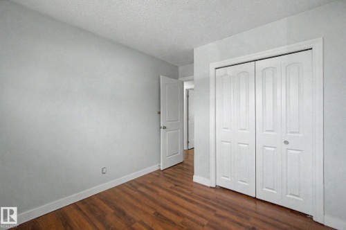 Room featuring wood-finish flooring, light gray walls, white baseboards, and a white bi-fold closet door - 1511 75 Street, Edmonton, AB 