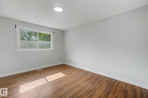 Room featuring wood-finish flooring, light grey walls, and white baseboards - 1511 75 Street, Edmonton, AB 