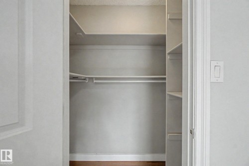 Built-in closet system featuring multiple shelves and hanging rods, wood-finish flooring, and white painted walls - 1511 75 Street, Edmonton, AB 