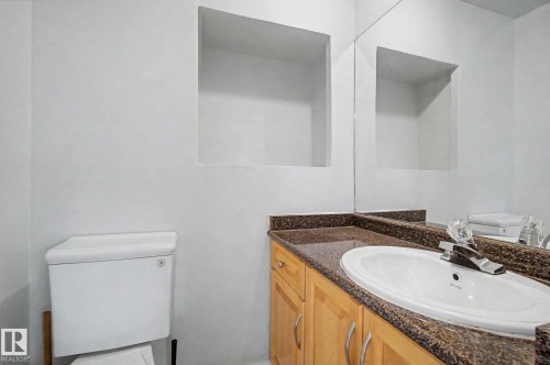Bathroom vanity featuring light wood cabinetry, a granite countertop, and an undermount sink - 1511 75 Street, Edmonton, AB 