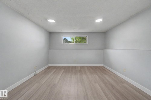 Spacious room featuring wood-finish flooring, light gray walls, and recessed lighting - 1511 75 Street, Edmonton, AB 