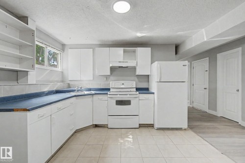 Kitchen featuring white cabinetry, blue countertops, tile flooring, a white range, and a white refrigerator - 1511 75 Street, Edmonton, AB 
