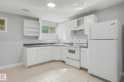 Kitchen featuring white cabinetry, grey countertops, white appliances, and tiled flooring - 1511 75 Street, Edmonton, AB 