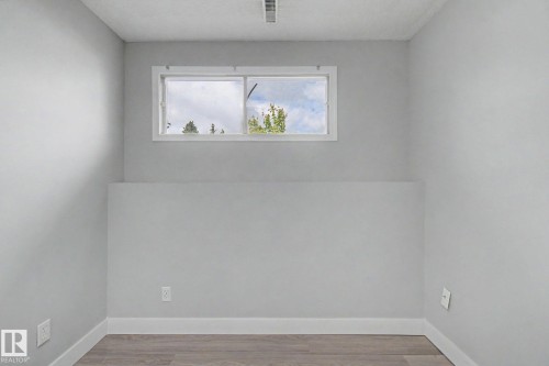 Room featuring light gray walls, white trim, and wood-finish flooring - 1511 75 Street, Edmonton, AB 