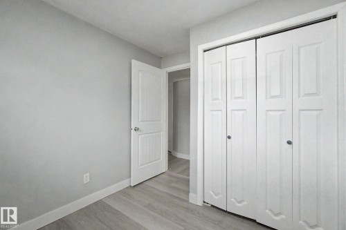 Bedroom featuring light gray wall paint, wood-finish flooring, white baseboards, and a bi-fold closet - 1511 75 Street, Edmonton, AB 