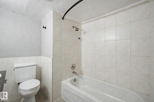 Bathroom featuring a white bathtub, ceramic tile shower surround, and a standard toilet - 1511 75 Street, Edmonton, AB 