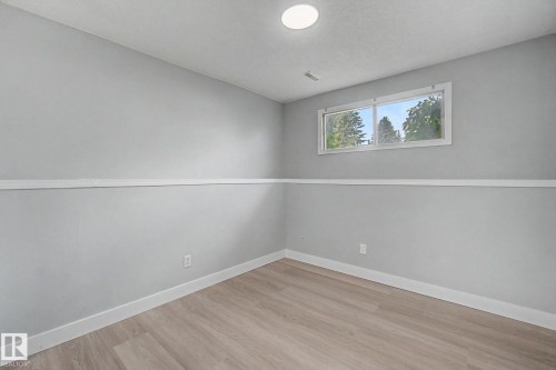 Neutral gray walls with white chair rail molding, wood-finish flooring, a double window, and recessed lighting - 1511 75 Street, Edmonton, AB 