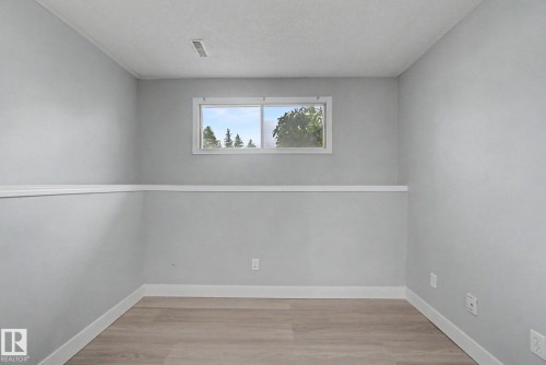 Room featuring wood-finish flooring, light grey walls with white chair rail molding, and a white-framed window - 1511 75 Street, Edmonton, AB 