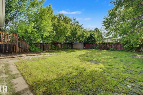 Expansive rear yard featuring a large wooden deck, established trees, privacy fencing, and a storage shed - 1511 75 Street, Edmonton, AB 