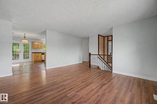Spacious living area featuring wood-finish flooring, light gray wall paint, and white trim - 1511 75 Street, Edmonton, AB 