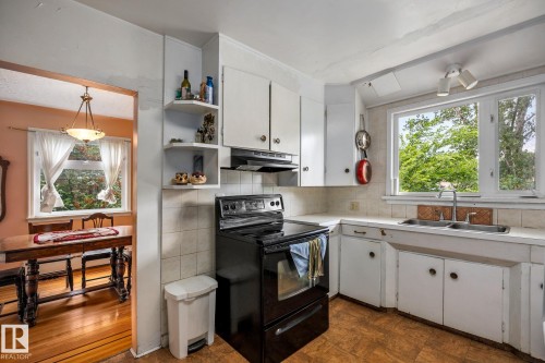 Kitchen featuring white cabinetry and a black electric range - 11022 110 Avenue, Edmonton, AB 