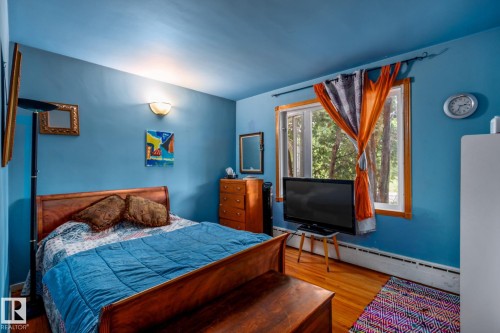 Room featuring wood-finish flooring, a double window with wood trim, and a wall-mounted light fixture - 11022 110 Avenue, Edmonton, AB 