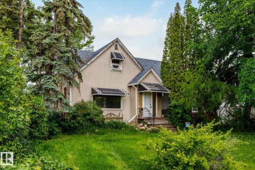 Stucco exterior with a peaked roofline, featuring decorative window awnings and a covered front entry with steps - 11022 110 Avenue, Edmonton, AB 