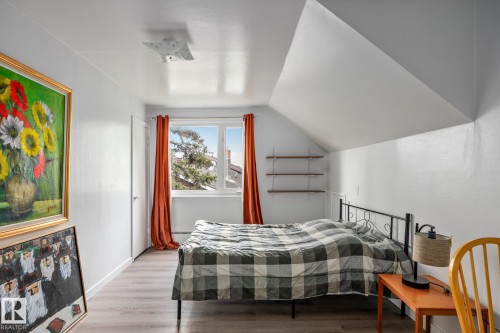 Attic bedroom featuring pitched ceilings, wood-finish flooring, a double-hung window, and built-in shelving - 11022 110 Avenue, Edmonton, AB 